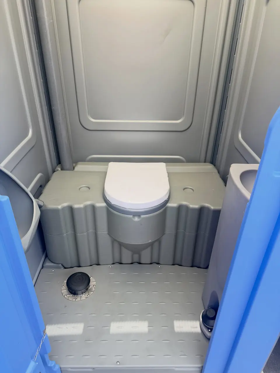 Flushing toilet seat inside a gray deluxe unit