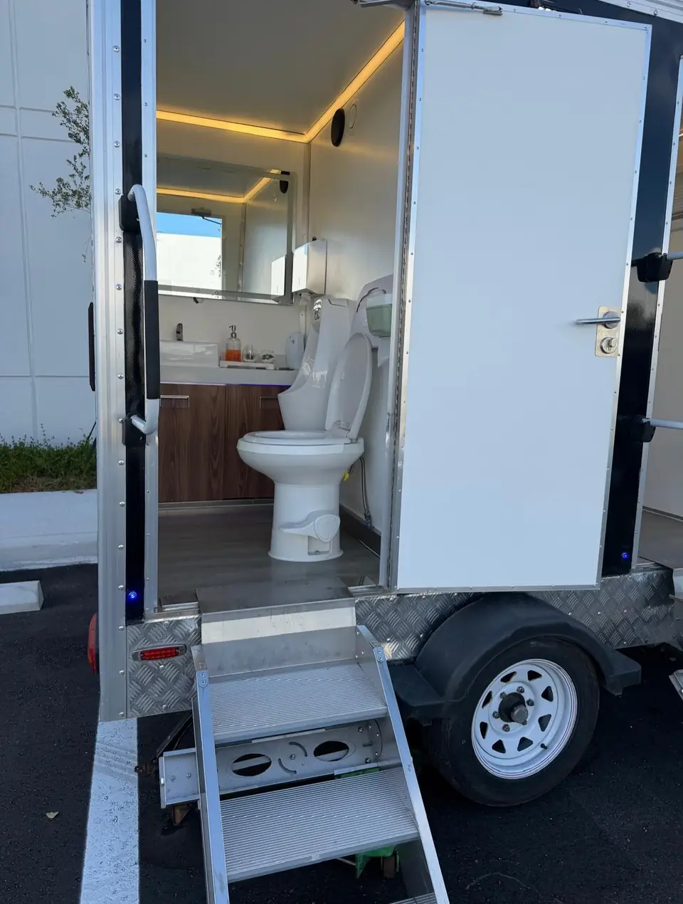 Restroom trailer door open with lit interior and entry steps